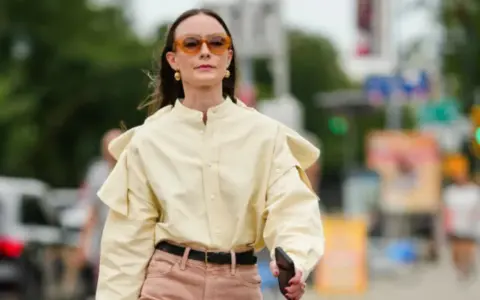 Donna con camicia gialla e pantaloni rosa. Un esempio di pantaloni rosa abbinamenti perfetti per un look casual chic.