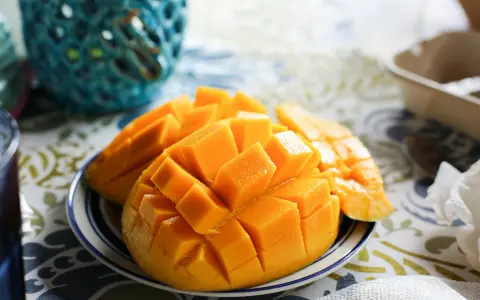 En skål med skivad mango, full av vitaminer, på en duk med mönster.