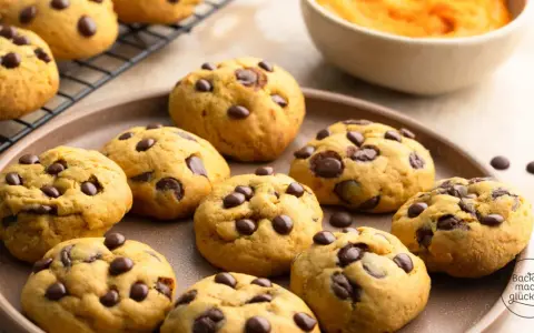 Saftige Schoko-Cookies, perfekt für jedes Cookies Rezept. Auf einem Teller und Gitterrost arrangiert, mit einer Schüssel Kürbispüree im Hintergrund.