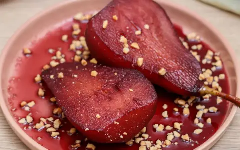 Peras al vino, tiernas y jugosas, bañadas en su propio jugo rojizo y espolvoreadas con trocitos crujientes.