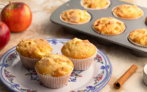 Frisch gebackene Apfelmuffins, die nach einem tollen apfelmuffins rezept duften. Daneben liegen Äpfel und Zimt.