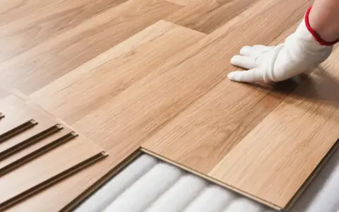 Instalación de suelo laminado. Mano con guante blanco colocando una tabla. Consulta el precio colocacion suelo laminado.