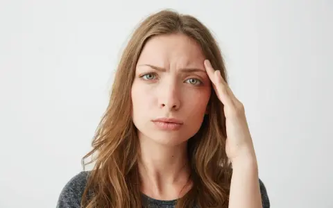 Donna con mano sulla tempia, espressione preoccupata, forse per lo stress ossidativo della pelle.