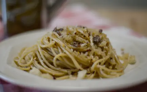 Un piatto di spaghetti conditi con pangrattato tostato, aglio, peperoncino e formaggio grattugiato, un classico della pasta mollicata.