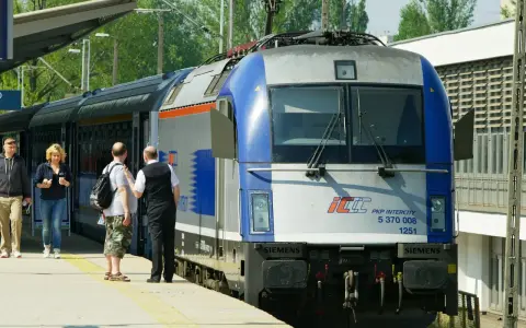 Pasażerowie czekają na pociąg PKP Intercity, gotowi do podróży z biletem wakacyjnym.