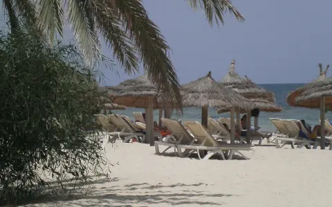Plaża na Djerbie z leżakami i parasolami. Ludzie odpoczywają, co sugeruje, że na Djerbie jest bezpiecznie.