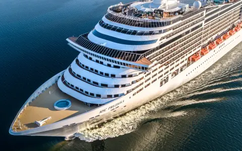 La MSC Preziosa solca il mare blu. L'equipaggio nave da crociera si prepara per un nuovo viaggio, con le scialuppe di salvataggio pronte.