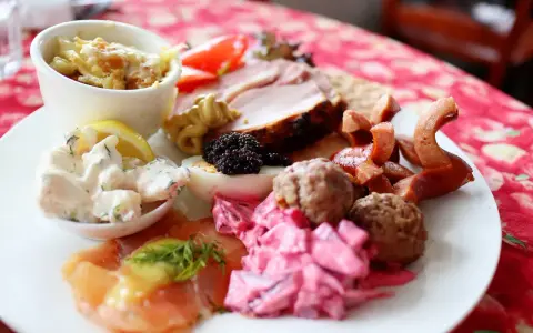En tallrik med julbordsfavoriter: sill, köttbullar, prinskorv, ägg, rom och skinka. En perfekt checklista för julbordet!