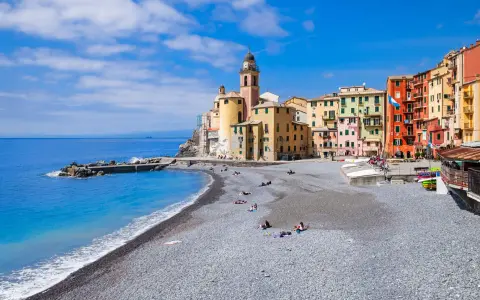 Un mare bello in Liguria, con la spiaggia di ciottoli e le case colorate di Camogli che si affacciano sull'acqua azzurra.