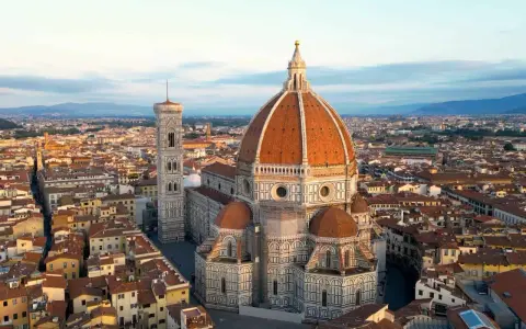 Vue aérienne de la **cattedrale Santa Maria** del Fiore et de son campanile, dominant les toits de Florence au lever du soleil.