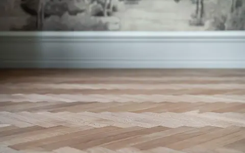 Nyligen slipad fiskbensparkett i ljust trä, redo att förvandla rummet.