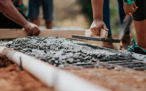 Dłoń wyrównująca świeży beton kielnią na budowie.