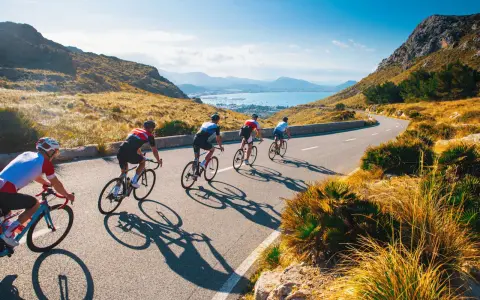 Ciclisti su una strada panoramica, esplorando i più bei percorsi in bicicletta in Italia, con il mare e le montagne sullo sfondo.