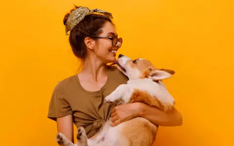 Uśmiechnięta dziewczyna z pieskiem corgi. Szukasz imiona dla psa na B? Może Borys albo Bąbel?