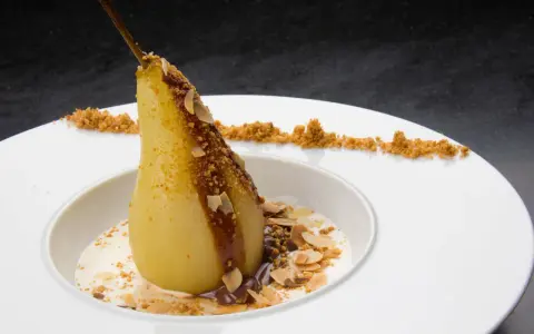 Un poire pochée, nappée de chocolat et amandes effilées, servie avec une crème légère. Un dessert poire chocolat rapide et gourmand.