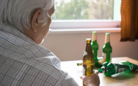 Starszy mężczyzna z butelkami piwa. Alkoholizm po 70. to trudna walka.