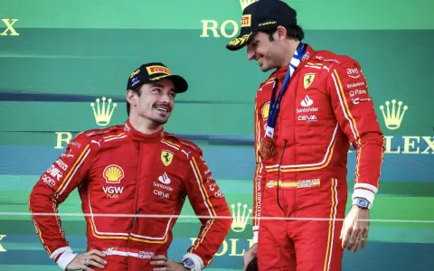 Carlos Sainz, con su altura destacada, sonríe en el podio junto a su compañero.