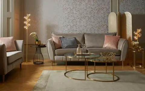 Przytulny salon glamour z beżową kanapą, różowymi poduszkami i złotymi dodatkami.