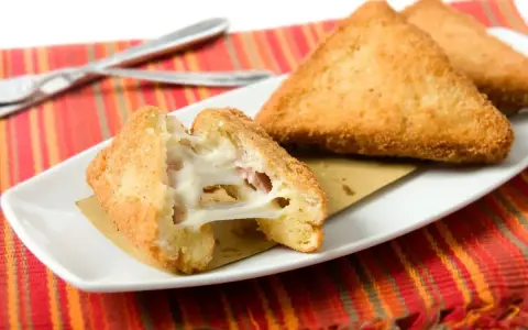 Mozzarella in carrozza dorata e filante, cotta in friggitrice ad aria, servita su un piatto bianco con tovaglietta colorata.