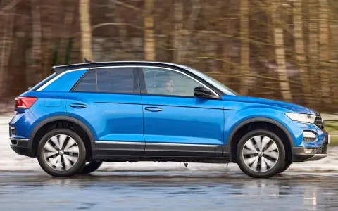 Blauer VW T-Roc fährt durch verschneite Landschaft. Keine Rede von vw t-roc kinderkrankheiten, nur Fahrspaß!