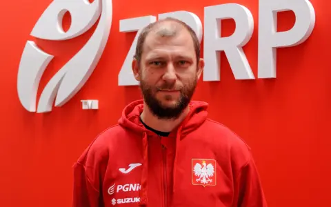 Marcin Wichary, w czerwonej bluzie z orłem, przed logo ZRP.