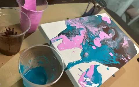 Peinture acrylique sur toile, avec des couleurs vives de rose, bleu sarcelle et marron qui coulent. Des gobelets en plastique contiennent les peintures.