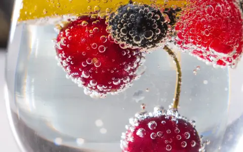 Erfrischendes Getränk mit Kirschen, Blaubeeren und Zitrone in sprudelndem Wasser. Der Unterschied Sodawasser und Mineralwasser liegt in der Kohlensäure.