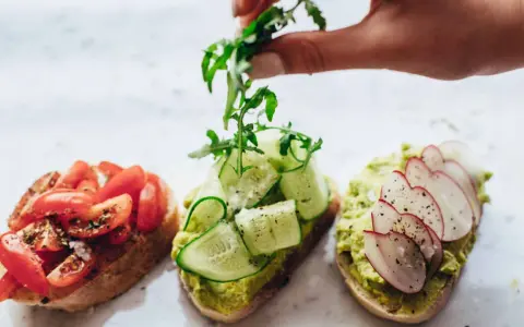 Tres tostadas gourmet: tomate, pepino y aguacate con rábano. La mejor variedad de aceite de oliva para tostadas realza sus sabores.