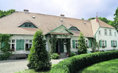 Urokliwy dwór Wybickich z zielonymi okiennicami i pnączami.