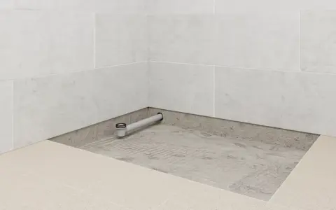 Installation d'un receveur de douche : un siphon est posé sur une chape avant le carrelage.