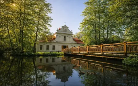 Urokliwy dworek otoczony zielenią, z drewnianym mostkiem i kaczą rodziną na stawie. Idealne miejsce na spędzenie **roztocze w jeden dzień**.