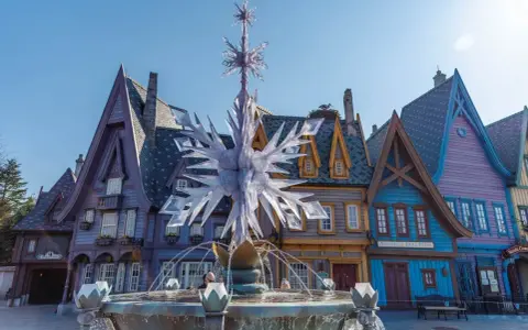 Ein eisiger Brunnen mit Schneeflocken-Dekor vor bunten Häusern, wie in einem **frozen Disneyland**.