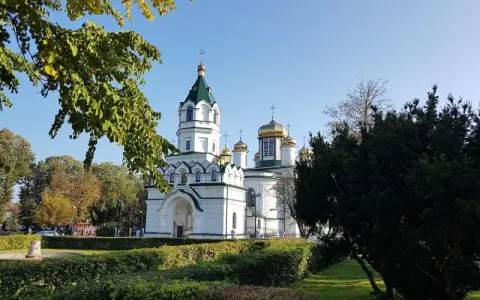 Biała cerkiew ze złotymi kopułami, otoczona zielenią. Piękny widok na szlak tatarski w słoneczny dzień.