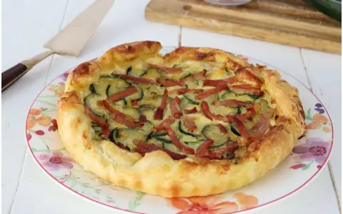 Torta salata con zucchine e speck, dorata e invitante, pronta per essere gustata.