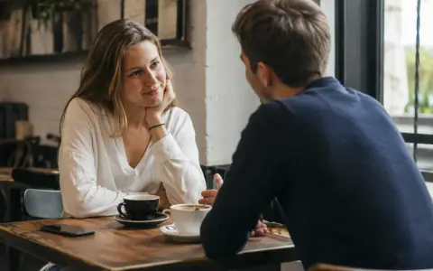 Para rozmawia przy kawie. Jej spojrzenie i gesty pożądania mówią więcej niż słowa.