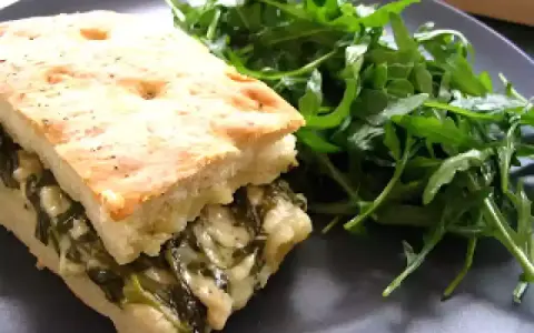 Une focaccia au fromage généreusement garnie d'épinards, servie avec une salade verte fraîche.
