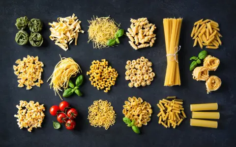Różnorodne włoskie dania z makaronem: od tagliatelle i spaghetti po farfalle i penne, z dodatkiem pomidorków i bazylii.