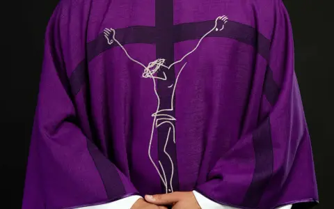 Fioletowa szata liturgiczna z haftowanym wizerunkiem Jezusa na krzyżu.