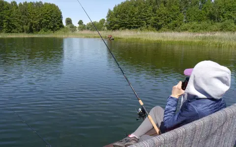 Osoba łowi ryby nad jeziorem Tuchlin, ciesząc się spokojem i pięknem natury.