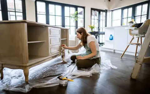 Mujer lijando muebles de madera antiguos para restaurarlos.