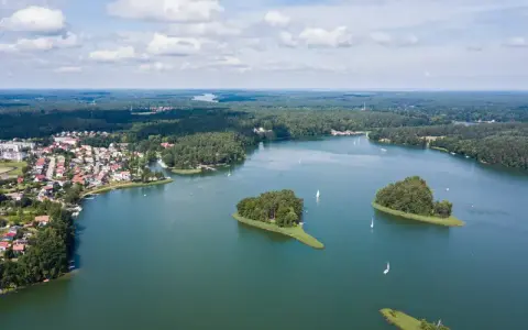 Malownicze jezioro z wyspami i żaglówkami, otoczone lasem i zabudowaniami. To widok, który potwierdza, że to jedne z najpiękniejszych jezior w Polsce.