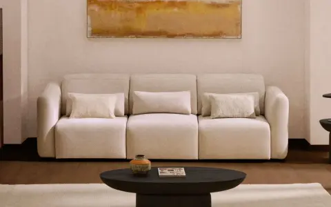 Sofá beige con cojines, mesa de centro oscura, alfombra clara y cuadro abstracto. Los colores feng shui crean un ambiente sereno.
