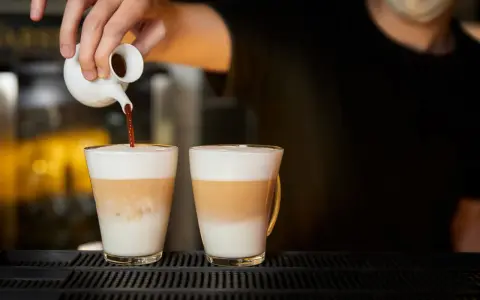 Barista wlewa espresso do dwóch latte macchiato. Zastanawiasz się, ile kcal ma latte macchiato?