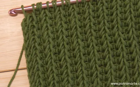 Punto tunecino con ganchillo en verde, ideal para mantas. El patrón crea un tejido denso y texturizado.