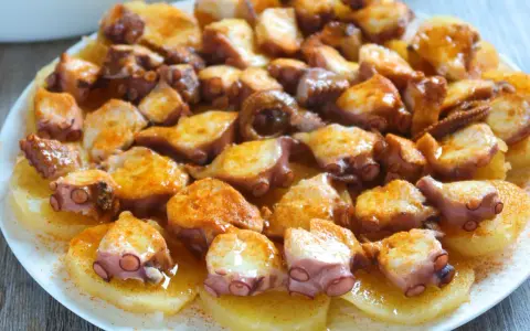 Pulpo a la gallega servido sobre patatas cocidas, con pimentón espolvoreado. ¡Un plato delicioso!