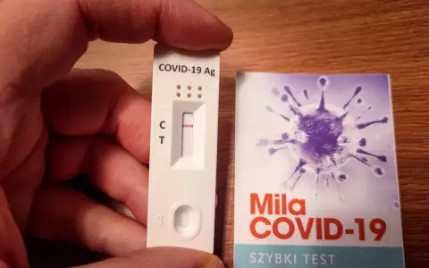 Szybki test antygenowy COVID-19 z jedną kreską kontrolną. Obok opakowanie z grafiką wirusa.