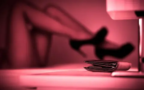 Portfel na stole, w tle niewyraźne nogi w szpilkach. To może być symbol tego, czym jest sexworking.