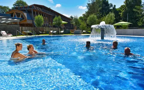 Entspannte Menschen genießen das Schwimmbad eines Kurortes in NRW. Ein Wasserspiel sorgt für Erfrischung.