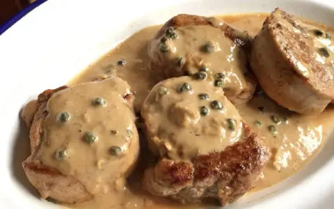 Cuatro medallones de solomillo a la pimienta en una cremosa salsa con granos de pimienta verde.