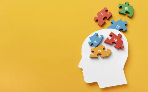 Biały profil głowy z kolorowymi puzzlami z cyframi wpadającymi do środka.